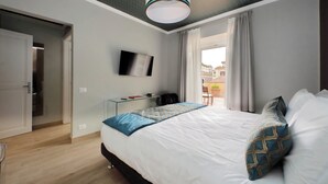 Habitación de hotel con cama, televisor, escritorio y vistas al exterior.