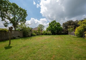 Enjoy the serene atmosphere of this spacious backyard with a variety of trees and a wooden fence.