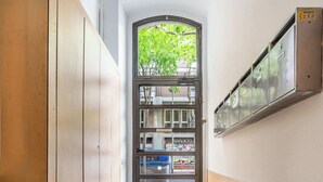 A hallway with wooden paneling, a glass door with a view of greenery outside, and metal lockers on the wall. - Pl Universitat Comfortable 3BD with private patio (Barcelona)