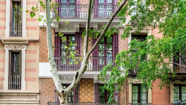 A multi-story building with balconies and a tree in front. - Pl Universitat Comfortable 3BD with private patio (Barcelona)