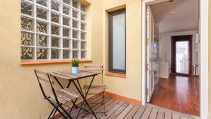 A wooden deck with a table and chairs, a potted plant, and a window with decorative glass. - Sunny Atico with Terrace in Pl Universitat! (Barcelona)