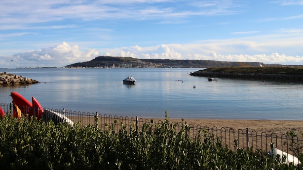 Une vue sur la côte, avec une mer calme, un petit bateau et une plage de sable.