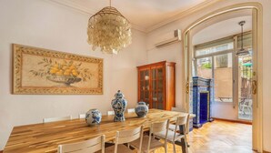 Un coin repas avec une table en bois, des chaises blanches, un vase et un buffet.