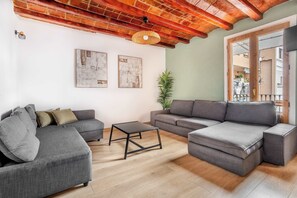 A living room with a sectional sofa, a coffee table, and a potted plant. - Modern 4 bedroom for 10 guests by Paseo de Gracia (Barcelona)