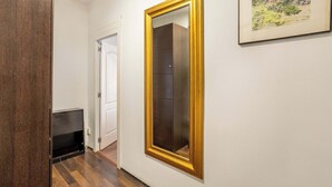 Ein Flur mit einem Holzschrank, einem großen Spiegel mit goldener Rahmung und einer Tür zu einem weiteren Raum.