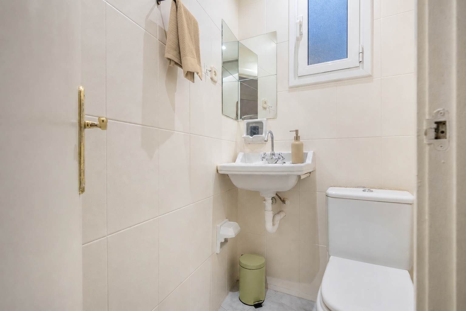 Baño pequeño con inodoro, lavamanos y cubo de basura.