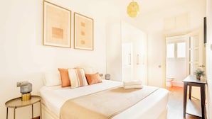 Ein Schlafzimmer mit einem Bett, Nachttischen, einer Hängelampe und gerahmten Bildern an der Wand.