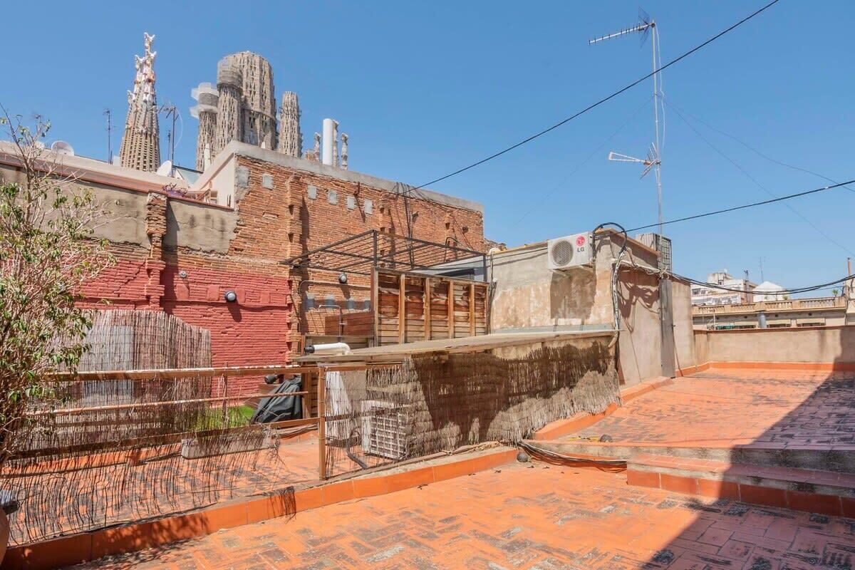 A rooftop terrace with a brick wall, a metal fence, and a clear view of the city skyline.