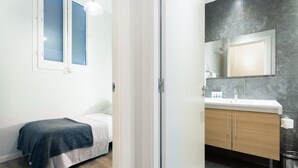 A bedroom with a bed, a bedside table, and a window with blinds. - Centric 2bedroom in Las Ramblas (Barcelona)