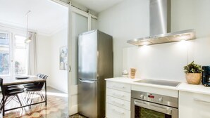 A modern kitchen with a stainless steel refrigerator, oven, and a white countertop.