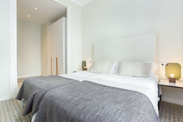 A hotel room with a large bed, a bedside table with a lamp, and a wardrobe.