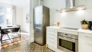 A modern kitchen with a stainless steel refrigerator, oven, and a built-in microwave. There is a dining area with a table and chairs, and a patterned floor.