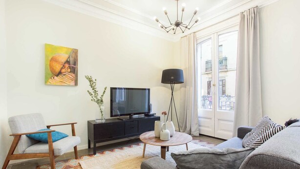 A living room with a sofa, armchair, TV, and a floor lamp.