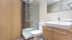 Une salle de bain moderne avec une douche à parois de verre, un lavabo blanc et des meubles en bois.