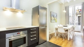 Une cuisine moderne dotée d’un four encastré, d’un réfrigérateur en acier inoxydable et d’un coin repas avec une table et des chaises.