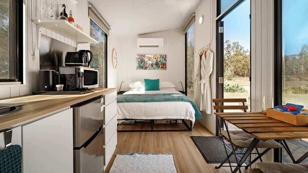 Een moderne, compacte kamer met kitchenette, een bed met uitzicht en een eethoek.