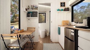 Een kleine keuken met een houten tafel, stoelen, een spoelbak en een vaatwasser.
