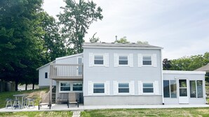 A two-story house with a balcony, a patio with outdoor furniture, and a stone pathway leading to the house.