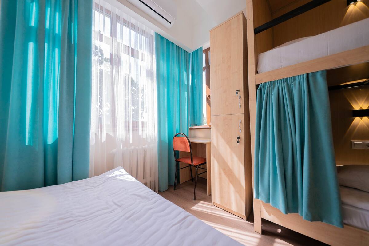 A room with a bed, a desk, and a bunk bed.