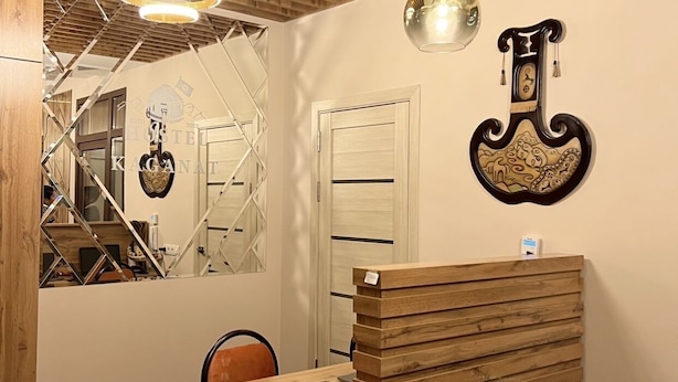 A reception desk with a wooden finish, a mirror, and a hanging light fixture. - Hostel Kaganat (Bishkek)