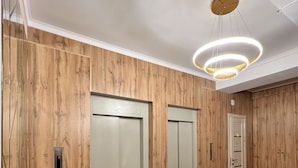 A hallway with wooden panel walls, black marble flooring, and a modern light fixture. - Hostel Kaganat (Bishkek)