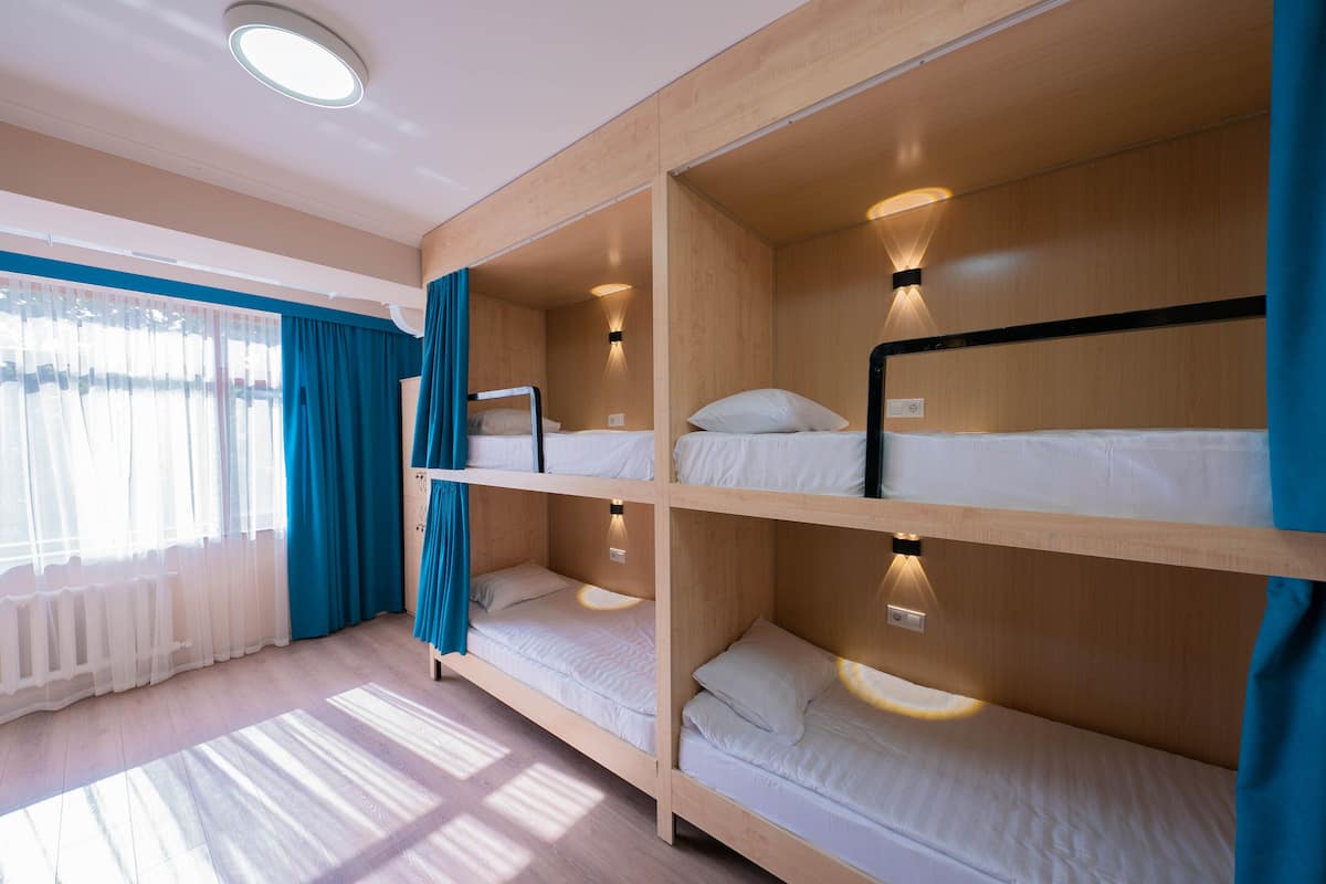 A room with bunk beds, a window with curtains, and a ceiling light.