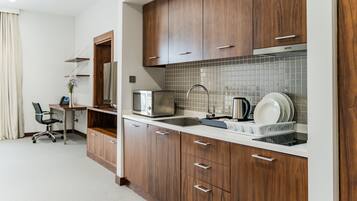 A modern kitchen with wooden cabinets, a microwave, a sink, and a countertop with dishware.
