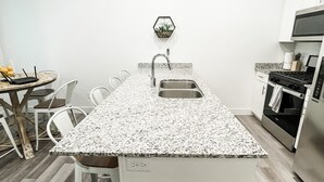 Eine moderne Küche mit Granitabdeckung, Edelstahlspüle und weißen Schränken.