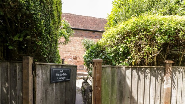Une porte en bois sur laquelle est apposée une plaque indiquant « 6A, Hock-Tide Cottage ».