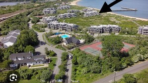 An aerial view of a residential area with multiple houses, a swimming pool, and a beach. - Spectacular Montauk Sunset in Gated Community - Perfect for Families! (Montauk)