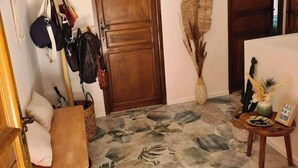 Une pièce avec une porte en bois, un banc, un porte-chapeau fixé au mur et un élément décoratif mural.