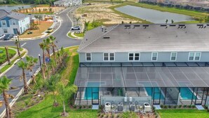A modern building with a large glass pool and outdoor air conditioning units. - Amazing home in Solterra Resort! (Davenport)