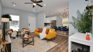 A modern living room with a yellow sofa, a coffee table, and a ceiling fan. - Cheerful House lKing Bedl Med Center, TSU, UH, Zoo (Houston)