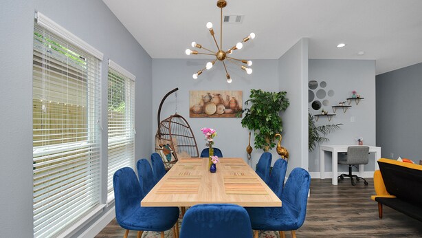 A dining area with a wooden table, blue chairs, a hanging light fixture, and a painting on the wall. - Cheerful House lKing Bedl Med Center, TSU, UH, Zoo (Houston)