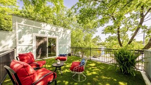 A patio with a red sofa, a small round table, and a chair. - Cozy Boho Guesthouse + Rooftop Deck in the Trees (Austin)