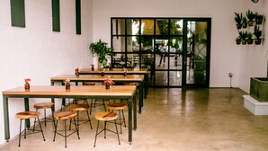 A cafe with multiple wooden tables and stools, a ceiling fan, and potted plants on the walls. - Cozy Boho Guesthouse + Rooftop Deck in the Trees (Austin)