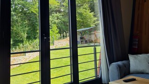 A room with large windows, a wooden ceiling, and a view of a garden and outdoor grill. - Kartepe Loft (Kartepe)