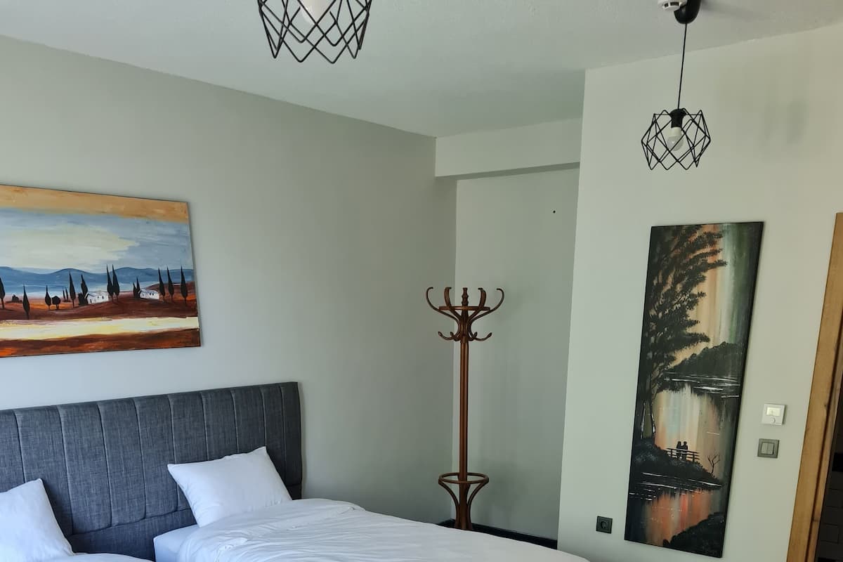 Ett hotellrum med två sängar, en klädställning och konstverk på väggarna.