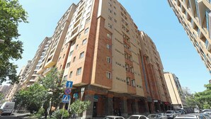A multi-story hotel with a modern architectural design, featuring balconies and a central entrance.