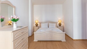 A bedroom with a bed, bedside lamps, a dresser, and a mirror.