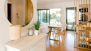 Een moderne eetruimte met een ronde spiegel, een witte console tafel en uitzicht op de natuur door grote ramen.