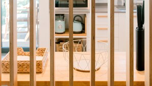 Een moderne keuken met houten kastjes, een inbouwoven en een keukeneiland met een mand van draad.
