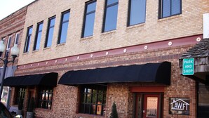A brick building with a black awning, a bench, and a 'Park and Shop' sign. - The Lawft, Suite 1,  Essentially 4 bedrooms each with attached Bathroom,No pets! (Russell)