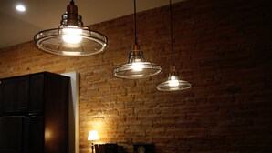 A kitchen with a brick wall, pendant lights, a refrigerator, and a table with a lamp. - The Lawft, Suite 1,  Essentially 4 bedrooms each with attached Bathroom,No pets! (Russell)