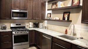 A modern kitchen with dark wood cabinets, stainless steel appliances, and a marble countertop. - The Lawft, Suite 1,  Essentially 4 bedrooms each with attached Bathroom,No pets! (Russell)