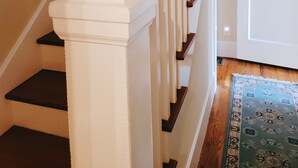 Eine Treppe mit weißen Balustraden und dunklen Stufen, die zu einer Tür führt.