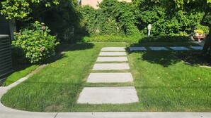 Ein gepflegter Garten mit einem steinbelagten Weg, der zu einem weißen Zaun führt.