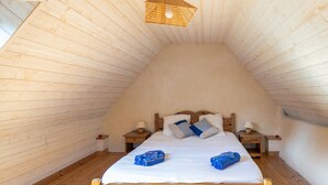 A cozy, wooden-paneled attic bedroom with a large bed, two nightstands, and a hanging light fixture. - Ty ar Hezeg - Gîte 3e avec terrasse privative (Telgruc-sur-Mer)