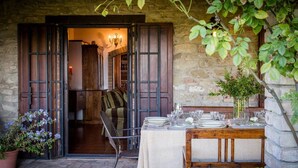 An outdoor dining area with a table set for four, a bench, and a potted plant. - Villa with panoramic pool • Passignano sul Trasimeno, Umbria (Passignano sul Trasimeno)