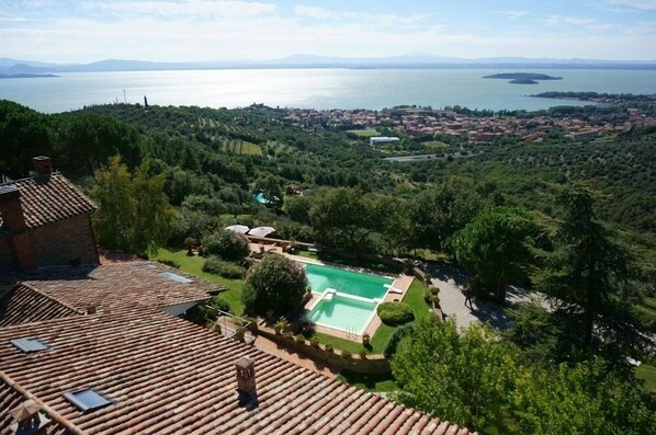 Eine Villa mit Swimmingpool, umgeben von üppiger Vegetation und Blick auf einen See sowie entfernte Inseln.
